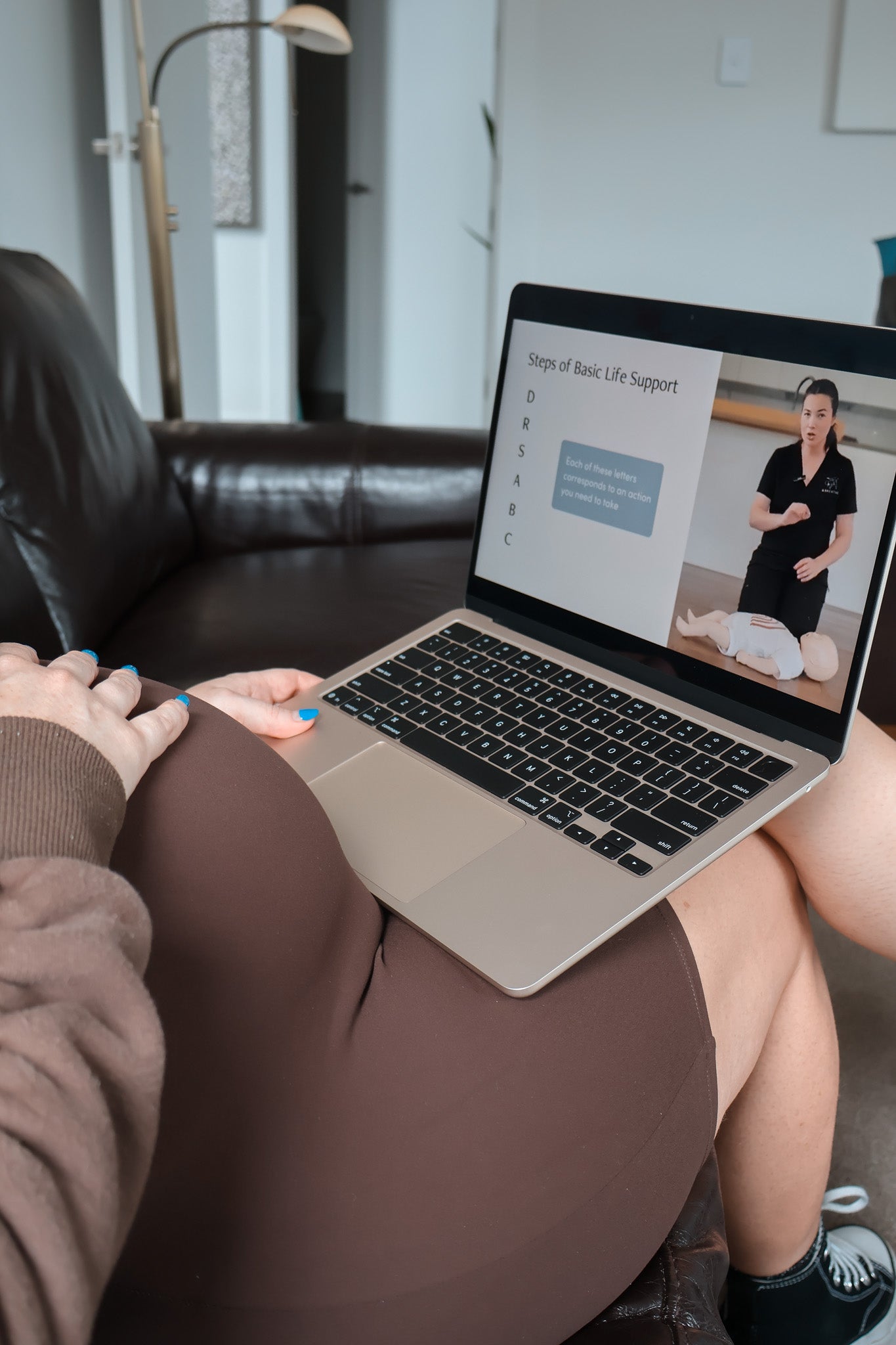 Person using a laptop on a couch accessing the online child and baby first aid course