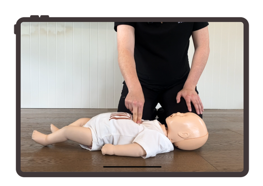 Person demonstrating CPR on a mannequin using a tablet device.